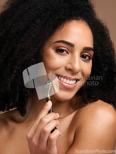 Image of Face portrait, skincare and black woman with roller in studio on a brown background. Makeup, cosmetics and happy female model holding jade stone product for facial massage, healthy skin and beauty.