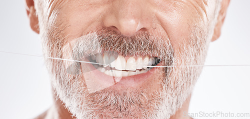 Image of Dental, floss and mouth of senior man in studio isolated on a gray background. Hygiene, cleaning and elderly male model with product flossing teeth for oral wellness, tooth care and healthy gums.