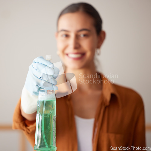 Image of Woman, spray bottle and cleaning service with a smile in a house or apartment for safety with gloves and chemical. Female cleaner showing liquid product to clean dirt, dust and bacteria at home