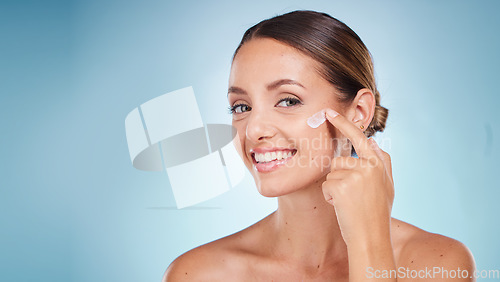 Image of Skincare, beauty and portrait of a woman with face cream for health, wellness and natural face routine. Cosmetic, happy and model with facial lotion, spf or creme isolated by a blue studio background