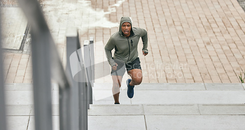 Image of Fitness, runner or black man running on stairs for training, exercise or cardio workout in Chicago. Mission, mindset or healthy athlete in hoodie with motivation or sports goals exercising on steps