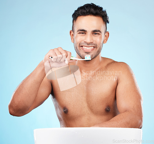 Image of Toothbrush, toothpaste and indian man portrait brushing teeth in blue background studio for hygiene wellness, cleaning or dental healthcare. Face, happy and smile for morning dental care routine