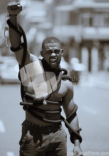 Image of Protest, fist and man in rope and handcuffs in city protesting against discrimination, oppression or slavery and racism. Black lives matter, justice and angry male in street fighting for human rights