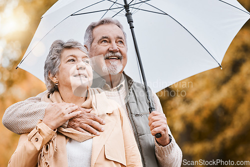 Image of Love, umbrella and nature with a senior couple outside together, standing in a park during winter or autumn. Forest, retirement and coutryside with a mature man and woman bonding outdoor for dating