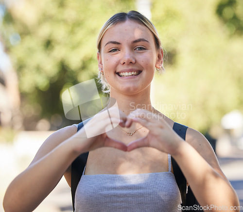 Image of Portrait, woman and heart shape in nature while outdoor for freedom, love and support for summer travel adventure. Happy young female with hand sign and backpack for motivation, peace and wellness