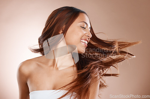 Image of Woman, shine and hair care for growth, wellness and natural with smile on studio background. Latino female, girl and shake head with confidence, healthy hair and beauty with cosmetics and carefree