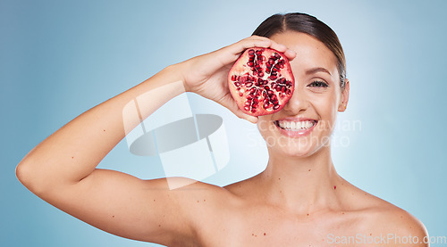 Image of Face portrait, skincare and woman with pomegranate in studio on a blue background. Organic cosmetics, beauty and female model with product, fruit or food for vitamin c, nutrition and healthy diet.