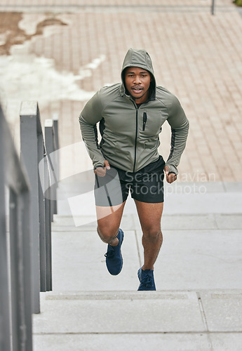 Image of Fitness, runner or black man running on steps in exercise, training or cardio workout in Chicago. Mission, mindset or healthy athlete in hoodie with motivation or sports goals exercising on stairs