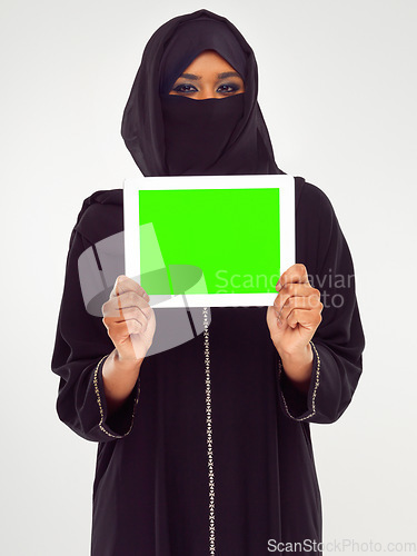 Image of Muslim woman, tablet and green screen for marketing, advertising or mockup against a grey studio background. Portrait of woman in hijab holding touchscreen with green chromakey screen or display