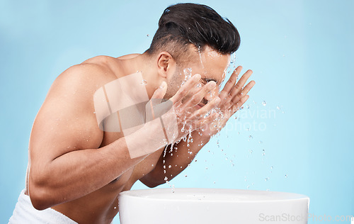 Image of Clean, grooming and man washing face with water for skincare, morning hygiene and care of body on a blue studio background. Beauty, wellness and model with a facial water splash for cleaning