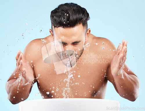 Image of Face, water splash and skincare of man cleaning in studio isolated on a blue background. Hygiene, water drops and male model washing, bathing or grooming for healthy skin, facial wellness or beauty.