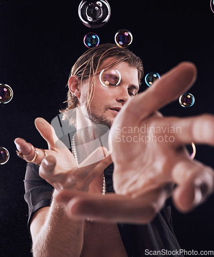 Image of Man, hands and bubbles in studio for magic, art performance or creative show by black background. Model, artist and soap with rainbow light, dark mystery aesthetic or theater presentation by backdrop