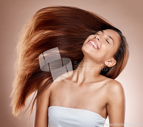 Image of Hair care, beauty and woman in a studio with healthy, long and brown hair after a salon hair style. Cosmetics, happy and female model from Brazil with a keratin or botox treatment by brown background
