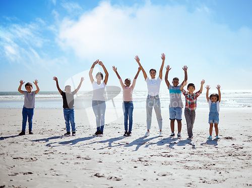 Image of Children, beach and friends in summer with their arms raised while standing on the sand by the sea or ocean. Portrait, kids and gesture with a boy and girl friend group by the coastal water