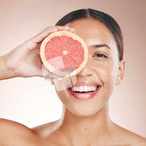 Image of Skincare, diet glow and woman with a grapefruit, marketing health and smile for detox food on a studio background. Vitamin c, nutrition and portrait of a dermatology model with fruit for wellness