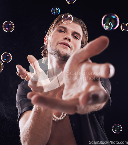 Image of Bubbles, hands and man in studio for magic portrait, art performance and creative by black background. Alluring model, soap and rainbow light with dark mystery aesthetic or sexy show by backdrop