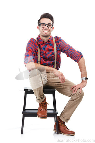 Image of Nerd, smile and portrait of a man sitting on a chair wearing geek clothing and glasses. White background, happiness and smiling model on a stool in a studio looking positive, smart and hipster