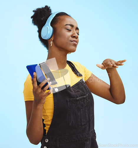 Image of Black woman, music and phone in studio with dance, dj hand gesture and listening by blue background. Gen z girl, streaming audio or online radio on internet, happy and fashion headphones by backdrop