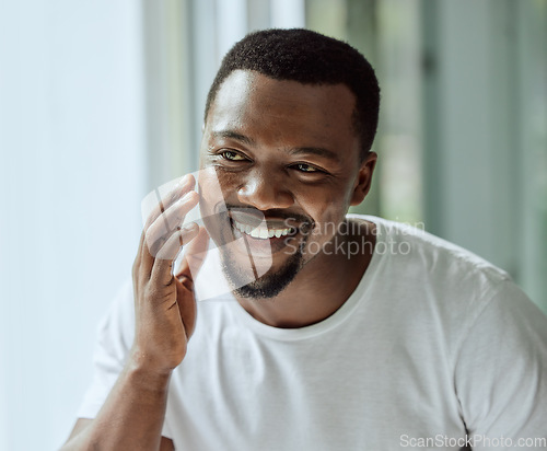 Image of Face, antiaging and skin with a black man looking in the bathroom mirror during his morning routine at home. Skincare, beauty and reflection with a handsome male grooming for wellness or natural care