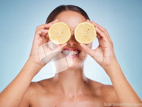 Image of Beauty, lemon and skincare with a model woman in studio on a blue background for natural treatment. Wellness, luxury and fruit with an attractive young female posing to promote health or skin care