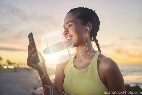 Image of Fitness, beach and woman with smartphone after running at sunset, online and streaming music or podcast in nature for exercise. Runner, relax and scroll social media after run, smile with earphones.