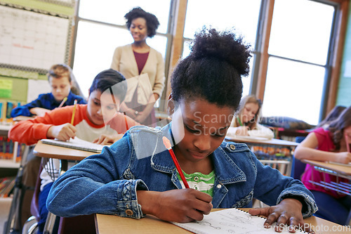 Image of Children, education and school with a student black girl writing in a book while sitting in class for learning. Study, notebook and scholarship with a female child at her desk in the classroom