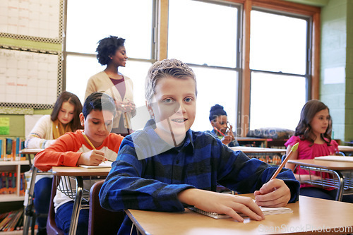 Image of Education, boy and student portrait in classroom with notebook for lesson notes and knowledge. School kids, learning and development of middle school children writing in books with happy teacher