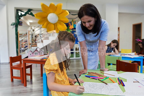 Image of Creative kids during an art class in a daycare center or elementary school classroom drawing with female teacher.