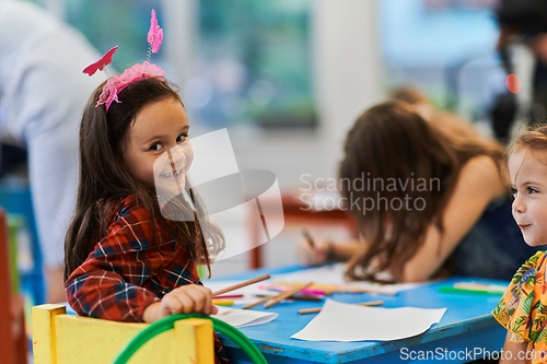 Image of Creative kids during an art class in a daycare center or elementary school classroom drawing with female teacher.