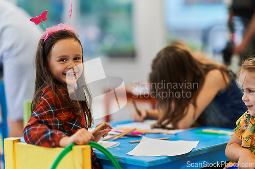 Image of Creative kids during an art class in a daycare center or elementary school classroom drawing with female teacher.