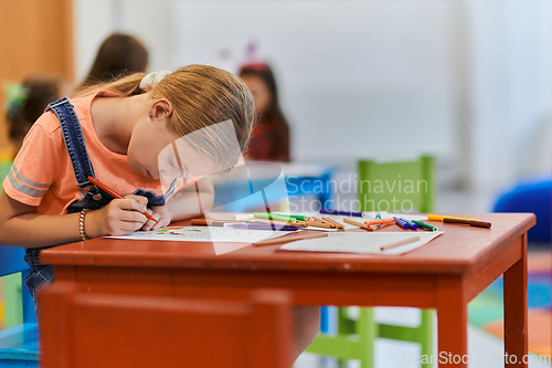 Image of Creative kids sitting in a preschool institution, draw and have fun while they get an education