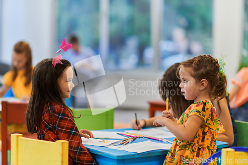 Image of Creative kids during an art class in a daycare center or elementary school classroom drawing with female teacher.