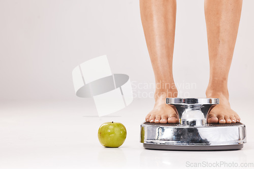 Image of Feet, scale and apple in studio on a gray background with mockup for diet, weightloss or detox. Food, weightscale and healthy eating with a barefoot woman weighing herself to tracl body progress