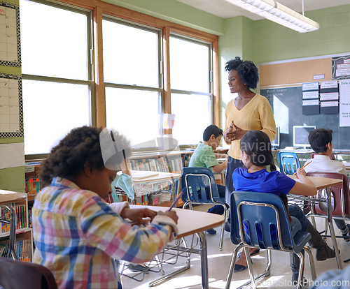 Image of School, children and teacher in a classroom while talking to kids to study and learn knowledge and education. Diversity group students in class writing and learning for future, development and growth