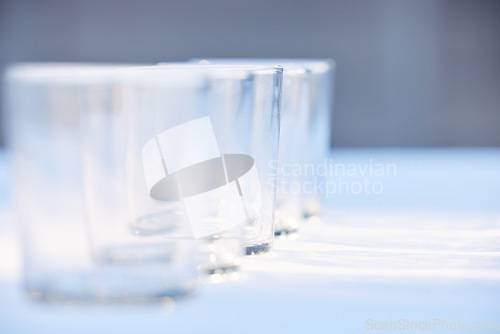 Image of Glass, crockery and mockup with a row of drinking glasses on a table in a studio or restaurant for fine dining. Space, glassware and drinks with a group of cups in a line for a beverage while dining