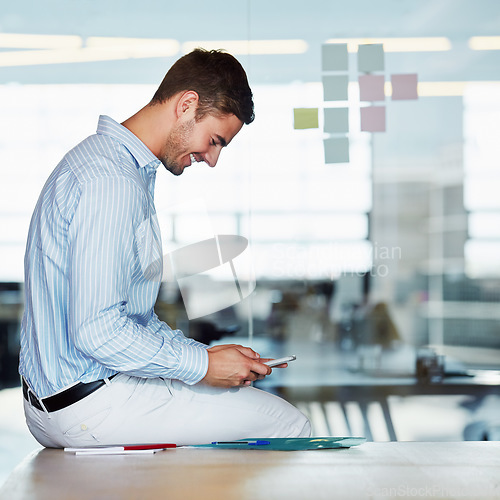 Image of Phone, office and business man on desk typing, texting or social media. Cellphone, break and happy male employee sitting on table with mobile smartphone for research, networking or internet browsing.