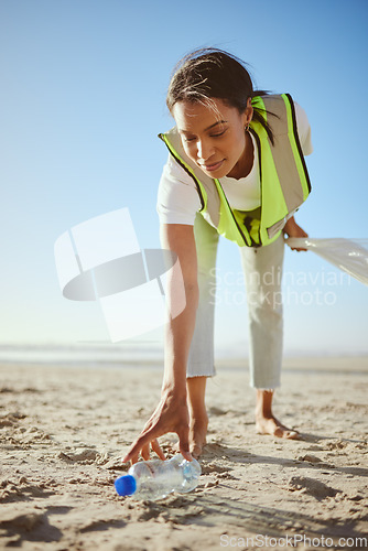 Image of Volunteer, charity and beach cleanup with a black woman picking up plastic bottle garbage from the sand. Recycle, cleaning or earth day with a female going green for the environment or sustainability