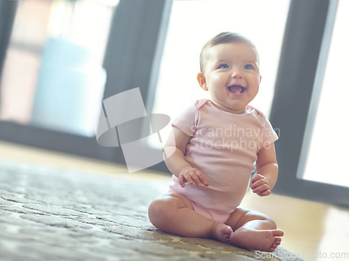 Image of Happy, cute and adorable baby girl in her home with a smile sitting and playing on the floor. Happiness, child development and excited beautiful infant child learning to crawl in a room at the house.