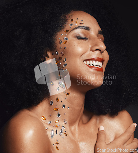 Image of Woman face, body art jewels or diamond rhinestones on black background studio in fashion sparkle, festival accessory or creative party crystals. Happy smile, makeup beauty model or skin cosmetic gems