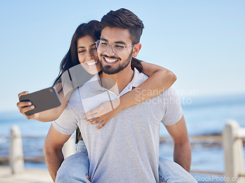 Image of Phone selfie, ocean and couple hug, bond and enjoy time together for peace, freedom or romantic date. Sea beach, memory photo and man piggyback woman on fun travel holiday in Rio de Janeiro Brazil