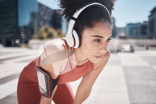 Image of Phone, fitness app and headphones, tired black woman runner stop to relax or breathe on city workout run. Health, urban training and wellness, woman on break from running exercise and streaming music