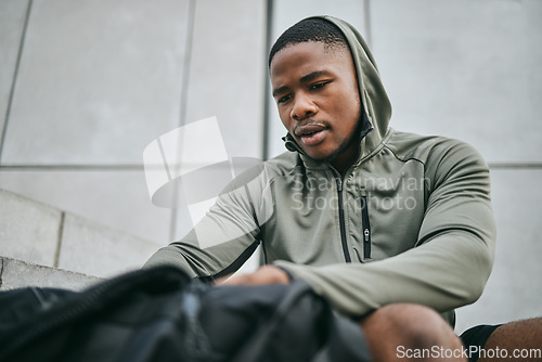 Image of Fitness, runner and sports bag with a black man athlete taking a break from his exercise in the city. Workout, training and running with a sporty male exercising for sport in an urban town alone