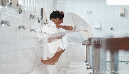 Image of Islam, ablution and man washing before prayer in bathroom at mosque in Iran, spiritual cleaning ritual. Islamic culture, water and worship, muslim guy in cleansing care routine to prepare for praying