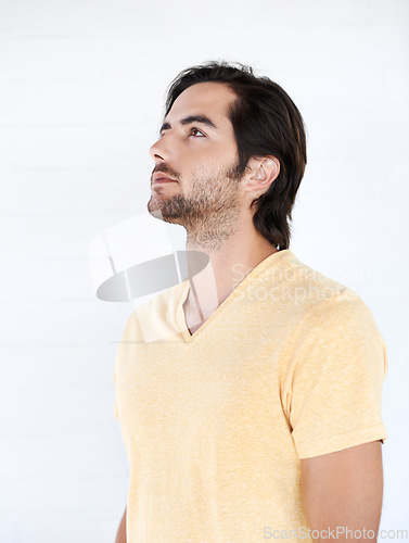 Image of Casual, thinking and man looking up in a studio while being thoughtful or wondering for an idea. Pensive, daydreaming and young male model from Canada with stylish tshirt isolated by white background