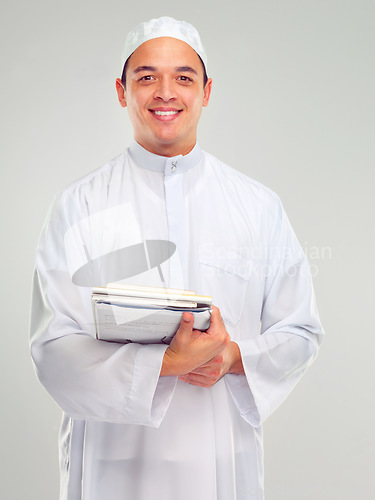 Image of Islamic man, smile portrait and books for learning standing in white background for Arabic culture. Young person, smile and religion faith, hope or studying for Muslim education isolated in studio