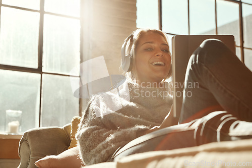 Image of Woman, sofa and tablet with happiness, music or communication on internet to relax in lounge. Girl, couch and movie with headphones, mobile tech and streaming app for comedy, laugh and happy in house