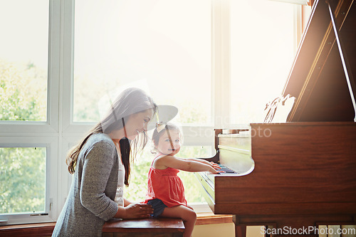 Image of Playing, music and mother and child with a piano, learning and happy together in a house. Love, smile and portrait of a playful baby with her fun mom teaching to play an instrument for happiness
