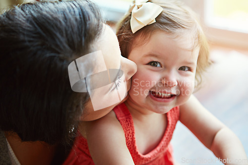 Image of Portrait of a baby with her mother kissing her cheek while playing, bonding and spending time together. Happy, smile and girl infant child sitting with her mom in their modern family home with love.