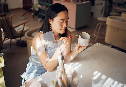 Image of Pottery, art and ceramics with an asian woman in a studio for design or a creative hobby as an artisan. Manufacturing, pattern and artist with a female potter sitting in her workshop as a sculptor