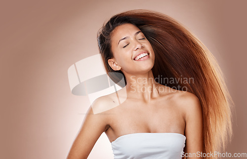 Image of Beauty, hair care and happy woman in studio with healthy, long and brown hair from salon. Cosmetics, health and female model from Brazil with keratin or botox treatment hair style by brown background